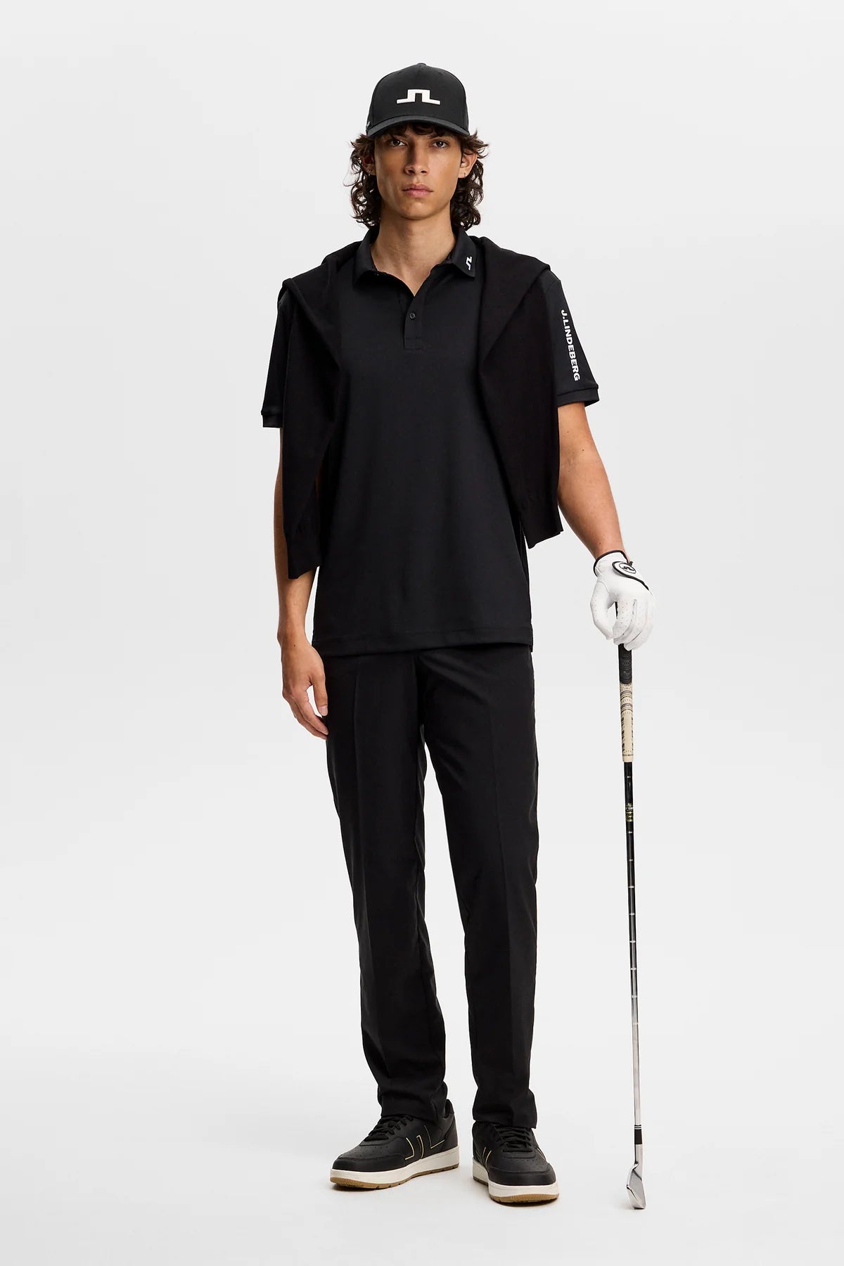 Black polo shirt with button placket and short sleeves, logo detail on sleeve