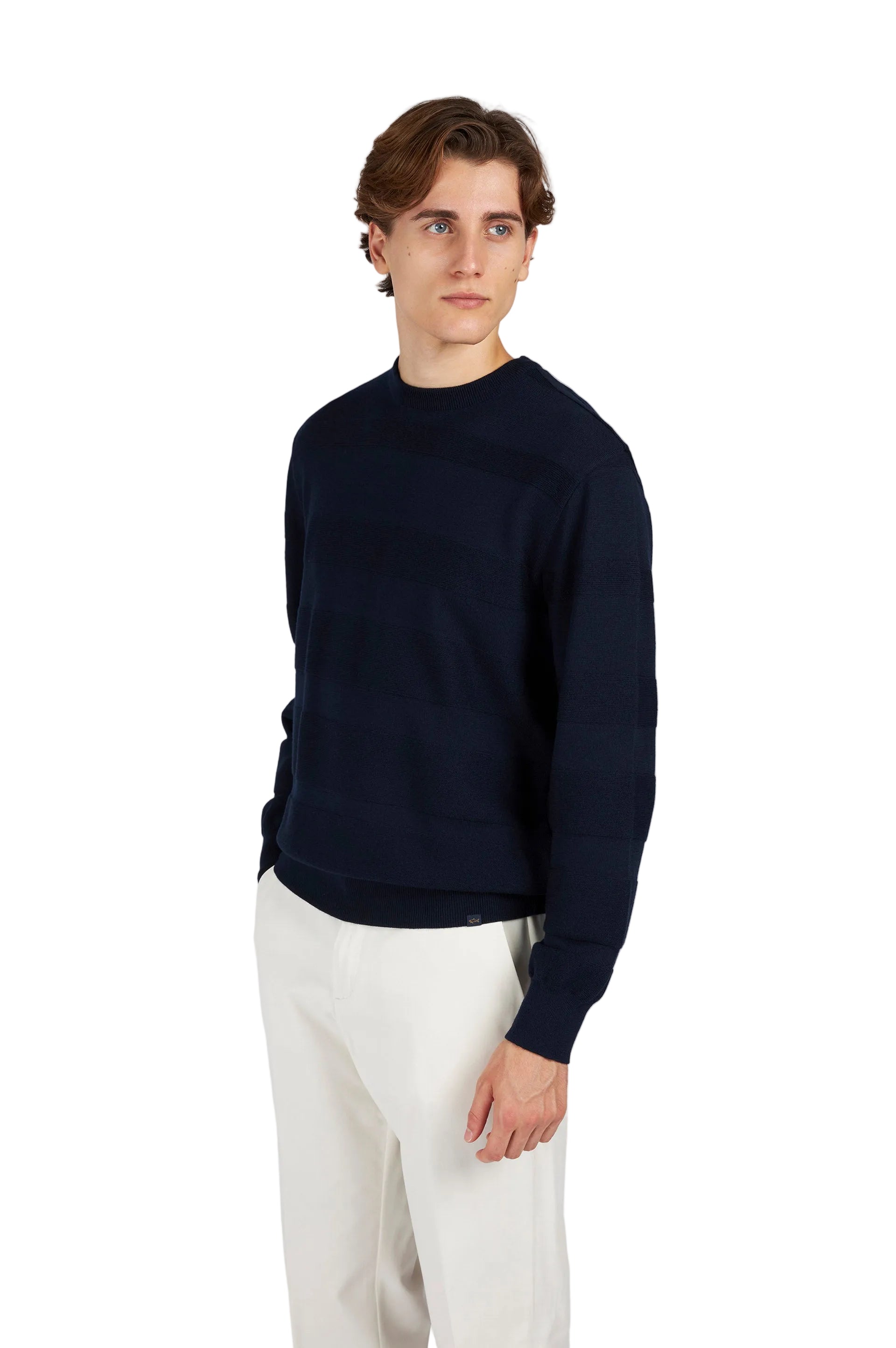 Man wearing a navy sweater and light-colored pants on a white background