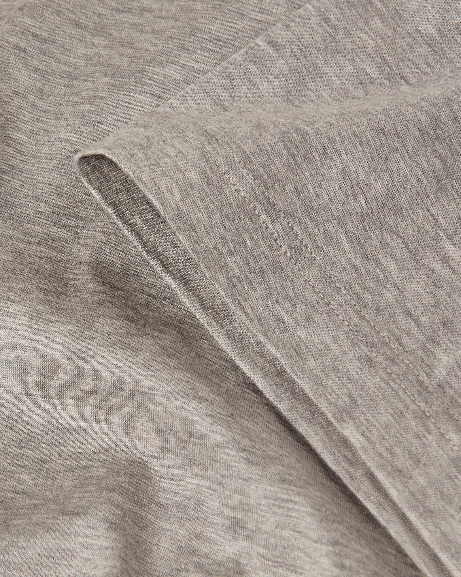 Grey marl T-shirt fabric close-up with stitched seams