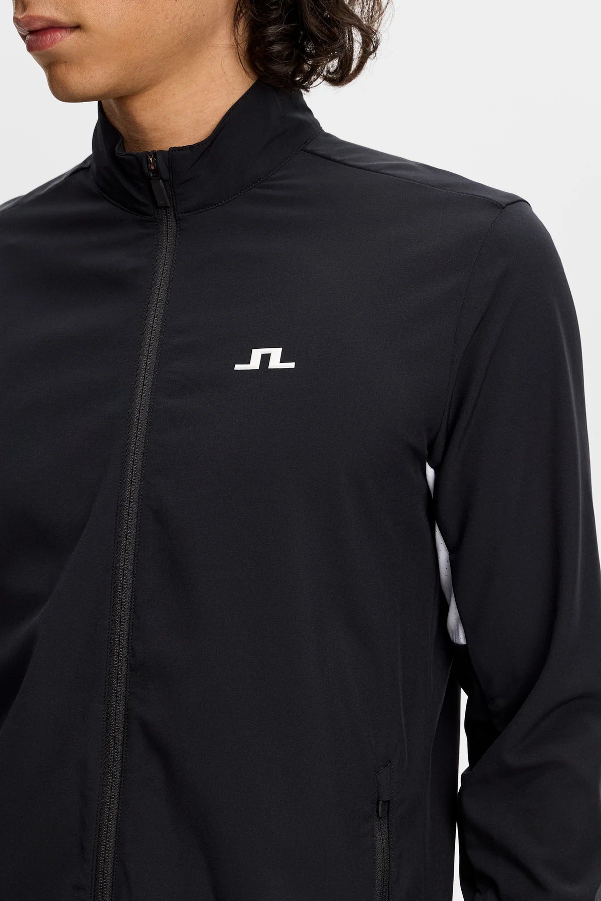 Black jacket close-up showing stand collar, full zipper, and JL logo on chest.