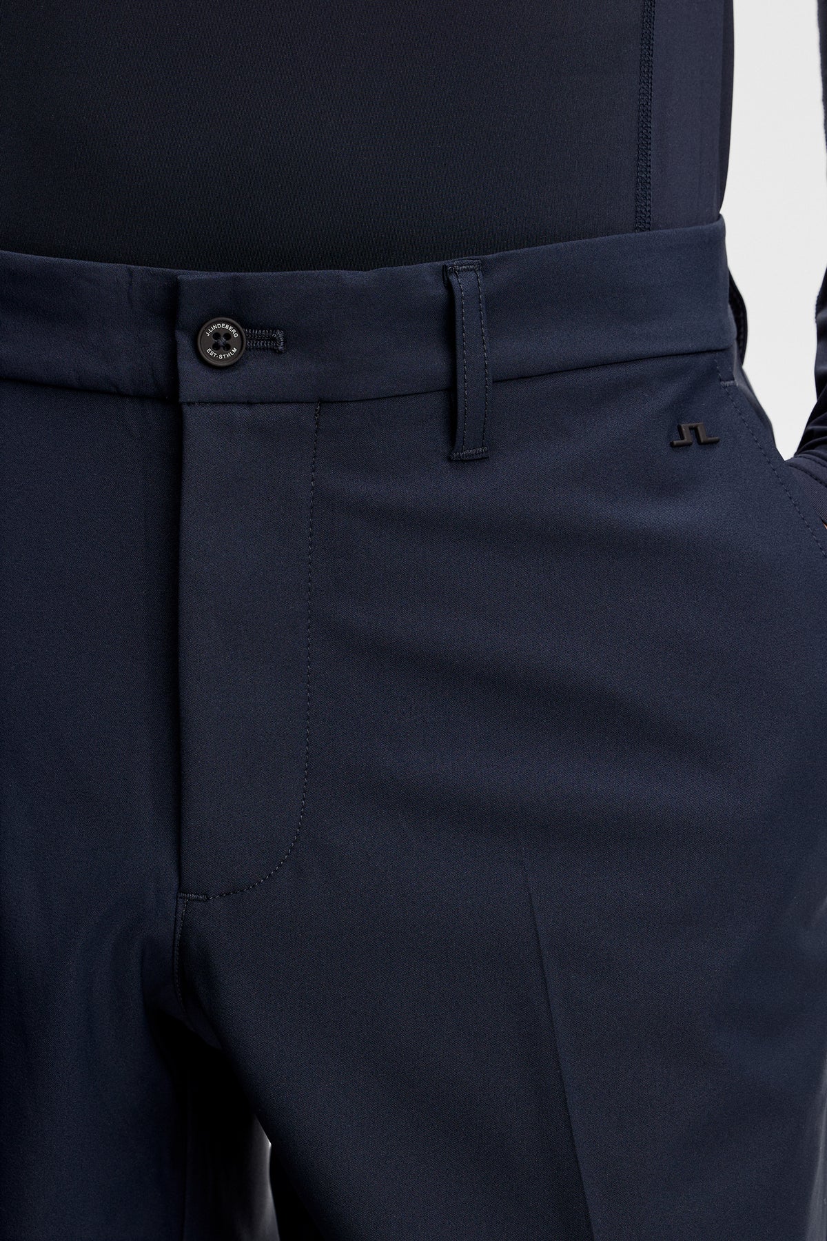 Navy trouser detail with waistband button, belt loops, and front crease