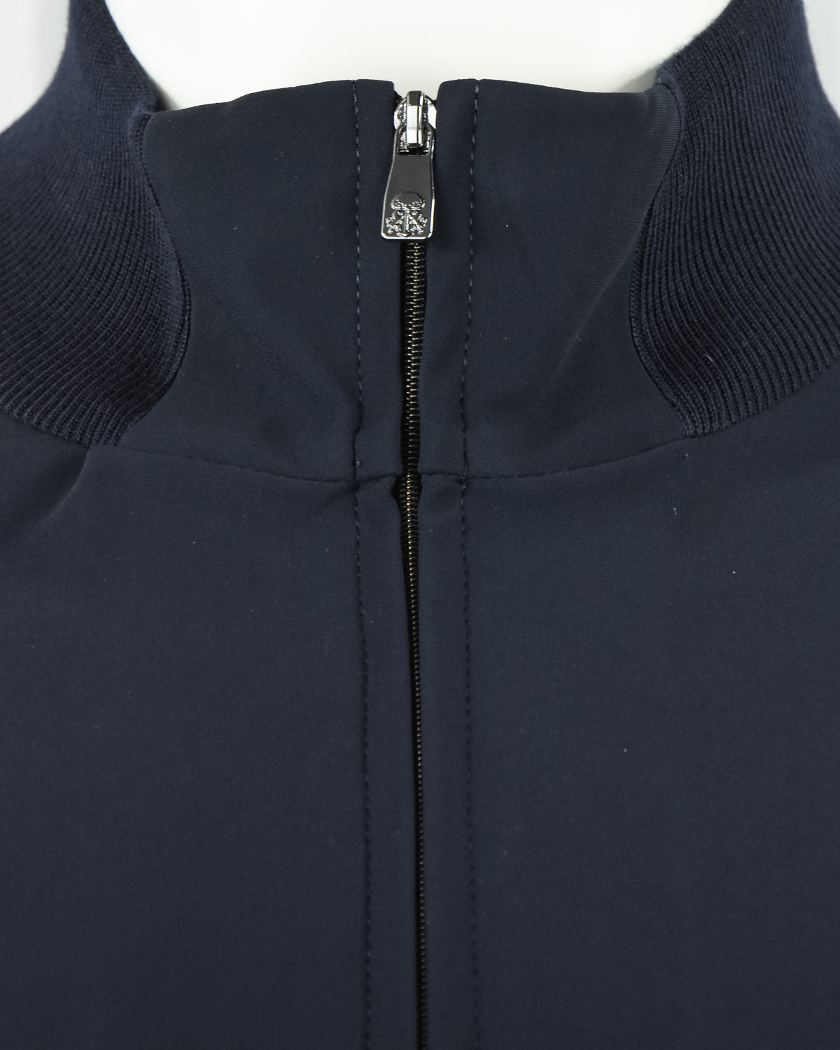 Stand collar close-up with dark navy zipper and metal branded pull tab