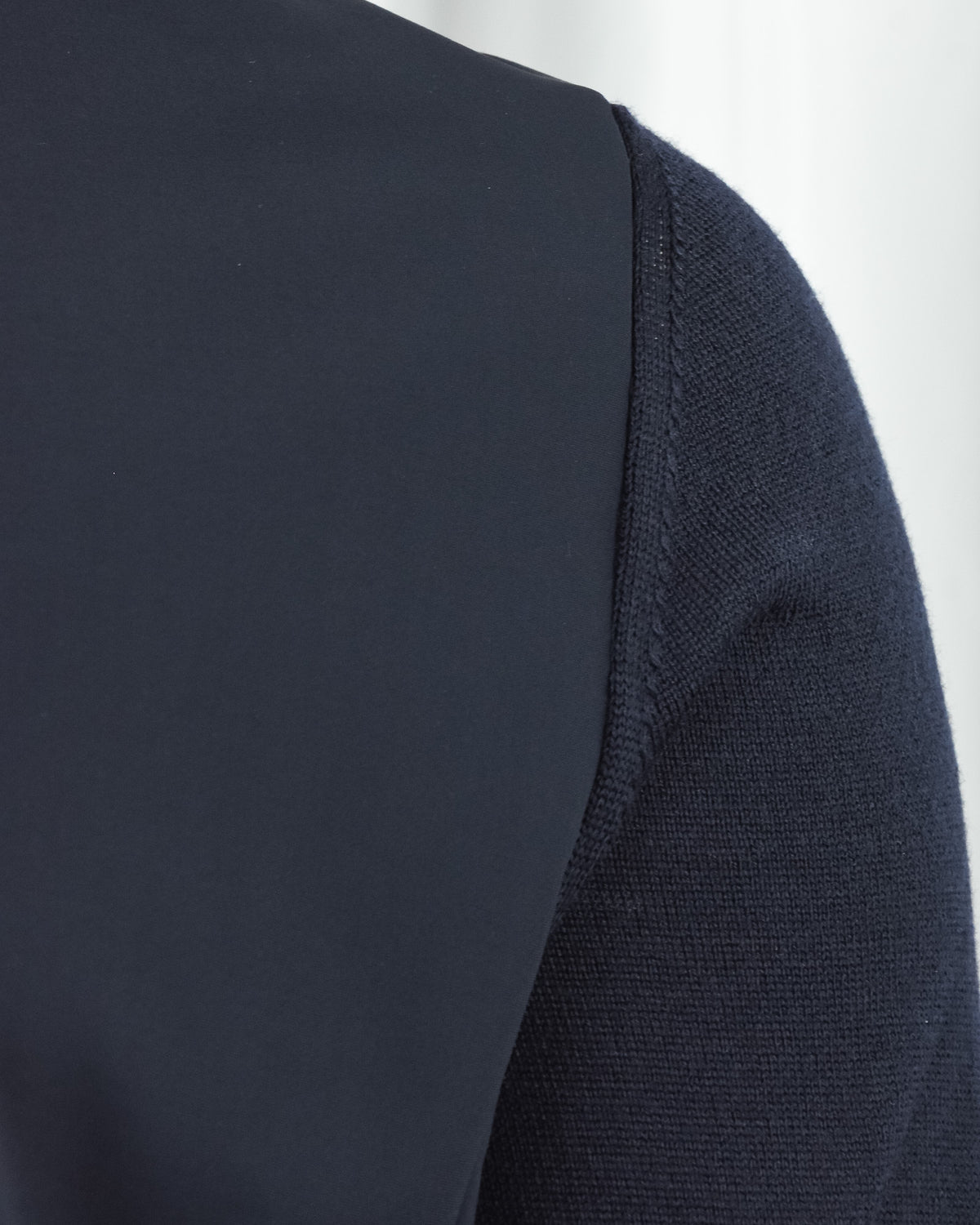 Side profile close-up showing dark navy knit sleeve trim and smooth front panel