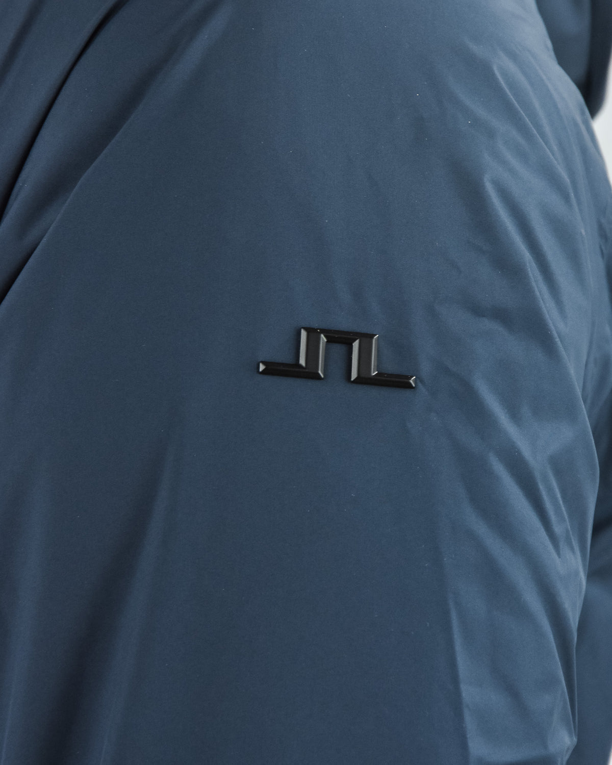 Navy down jacket chest logo detail with metal pin-style badge