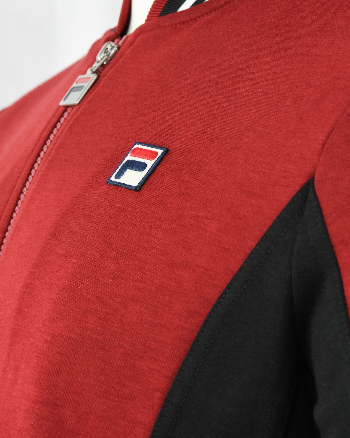 Red jacket chest with F-logo patch and full zipper front detail, black side panel.