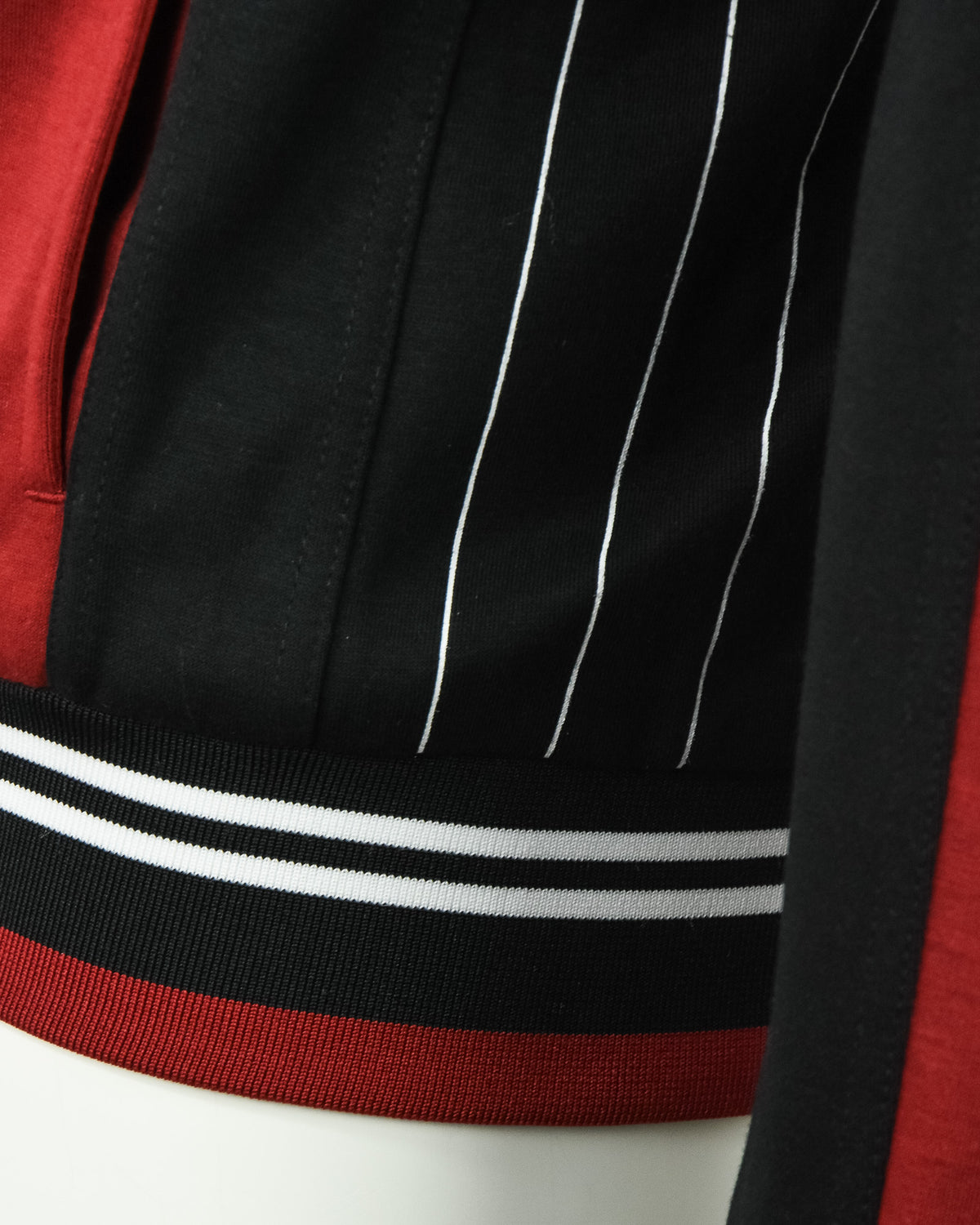 Ribbed striped hem on red-and-black track jacket with white and gray bands.