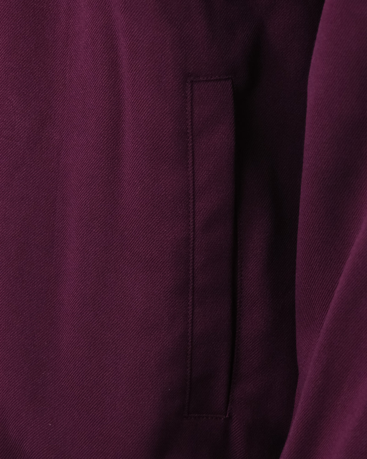 Close-up of purple track jacket side seam and stitched vertical pocket