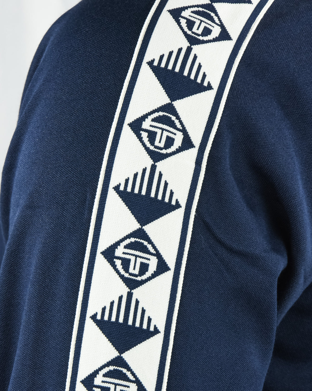 Navy track top: white geometric tape stripe with repeated logo patches