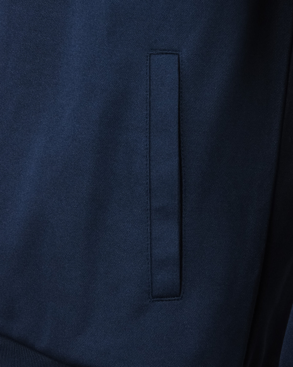 Navy track top close-up of front panel with vertical seam and tab