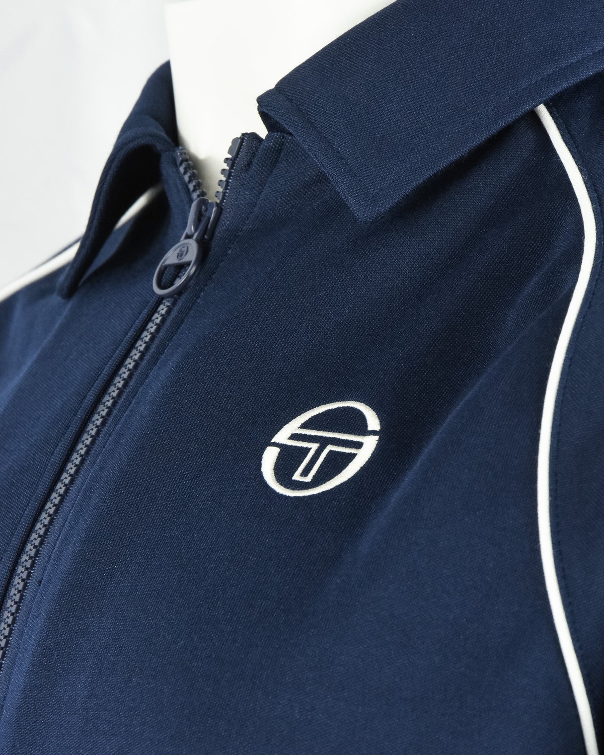 Navy track top chest logo with white piping along zipper placket