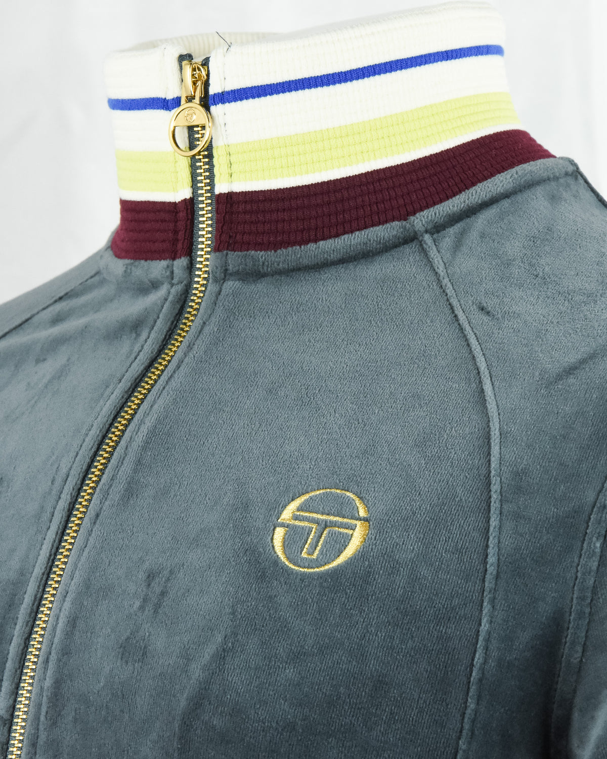 Dark teal velour track jacket with gold zipper, striped collar, and S logo