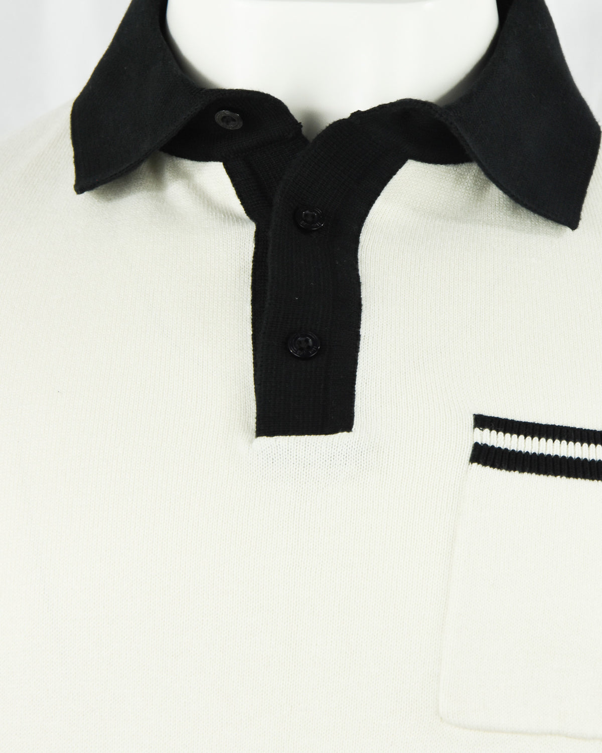 Cream knit polo showing black collar and placket with visible button details.