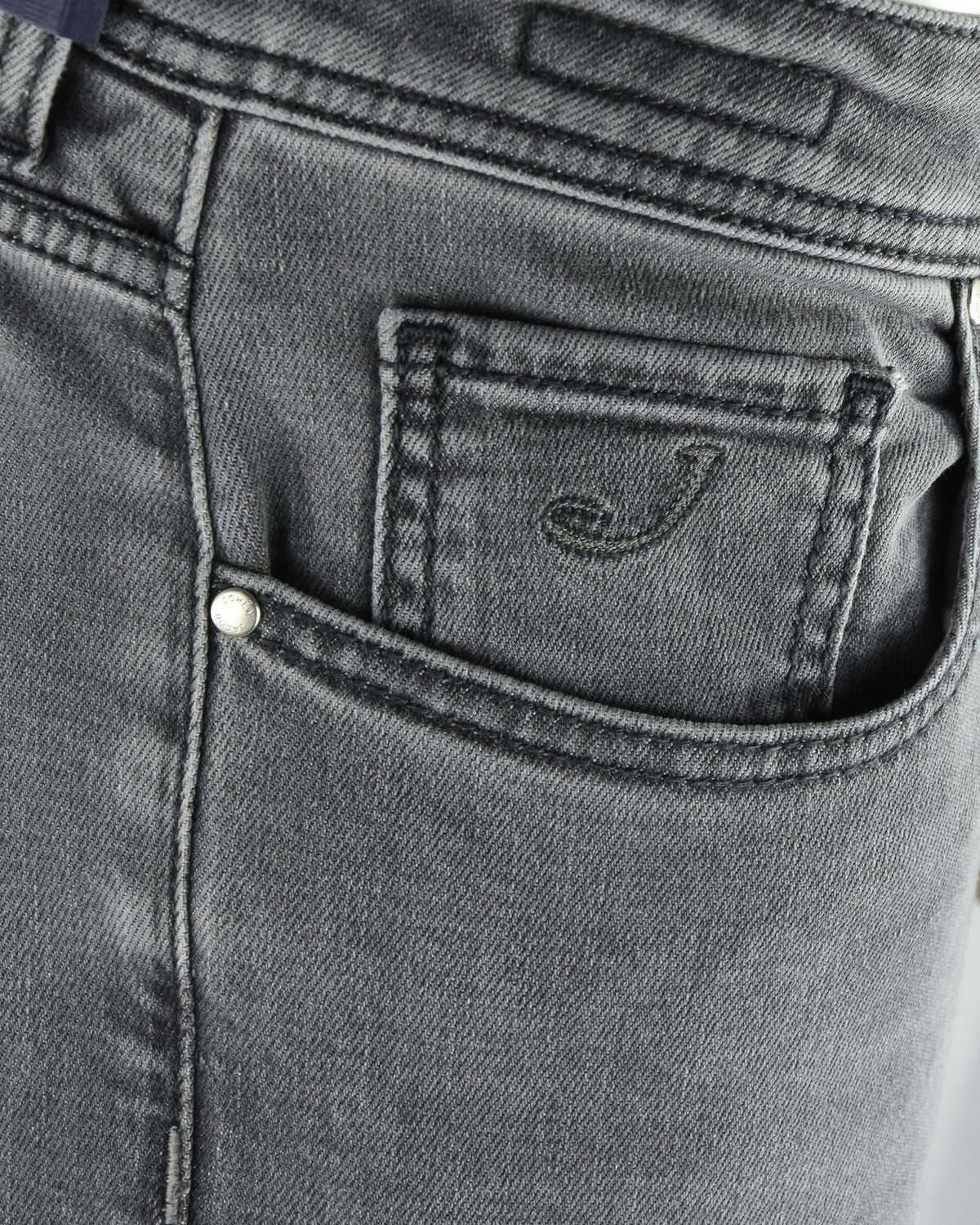Back pocket close-up on light grey denim jeans with small logo emblem