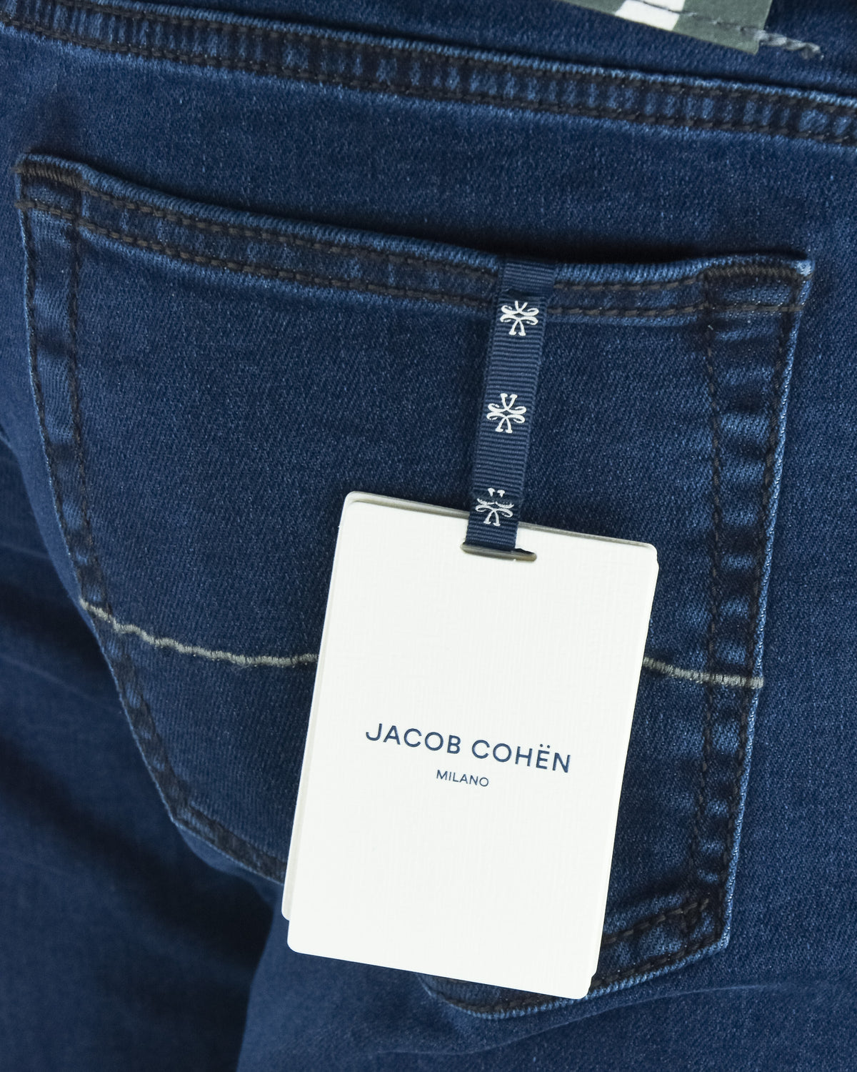 Dark blue denim jeans with hanging brand tag on front pocket