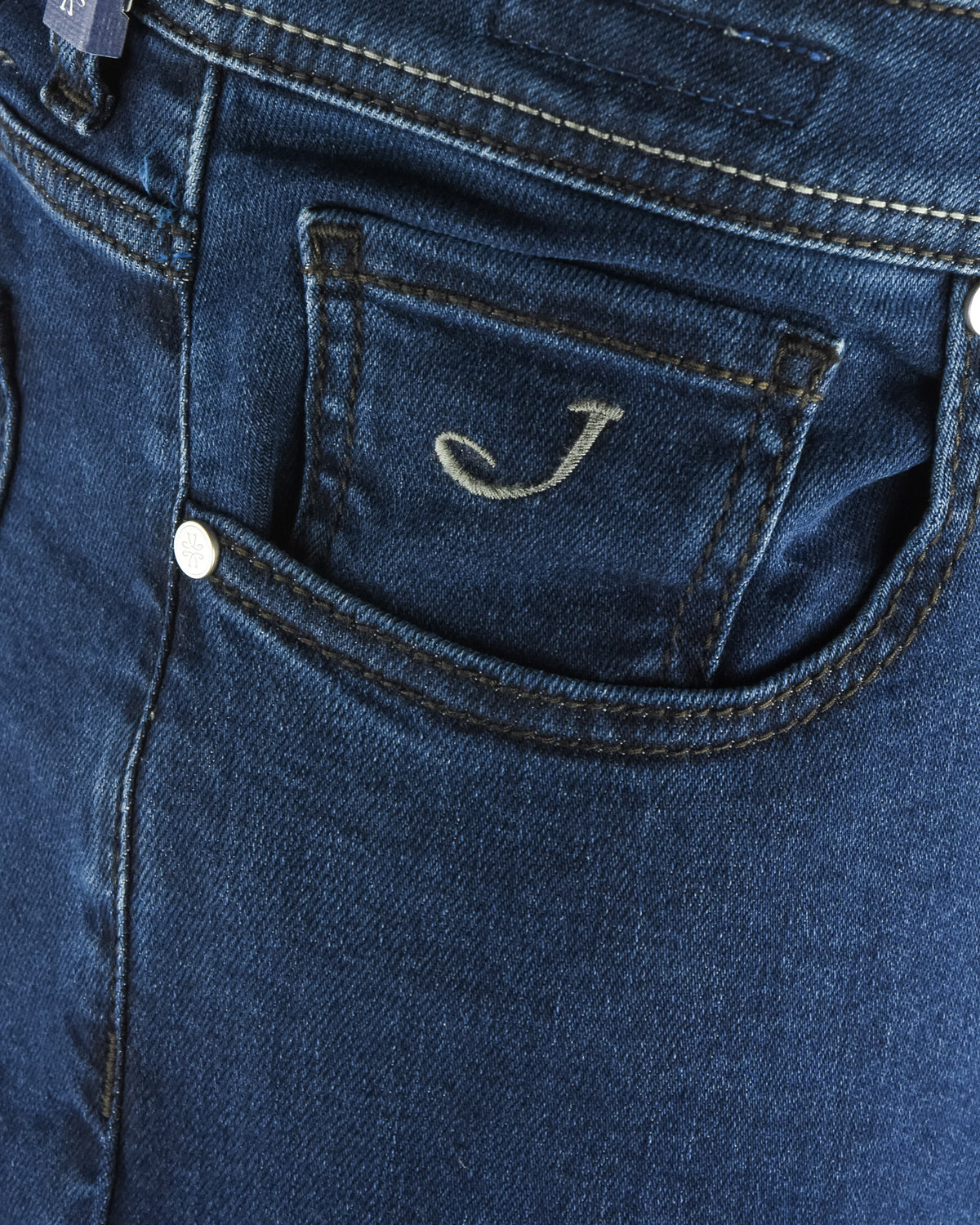 Dark blue denim jeans close-up of front pocket stitching and signature J