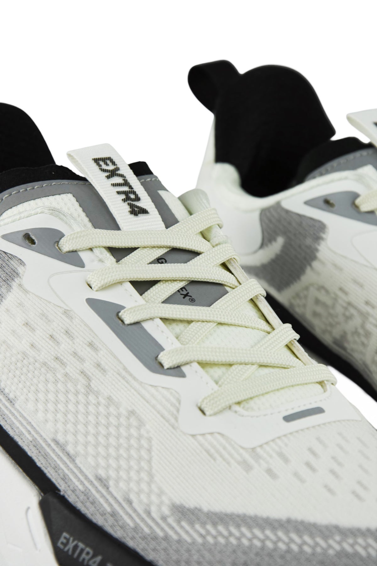 Close-up of white and gray waterproof runners with light green laces and logo patch