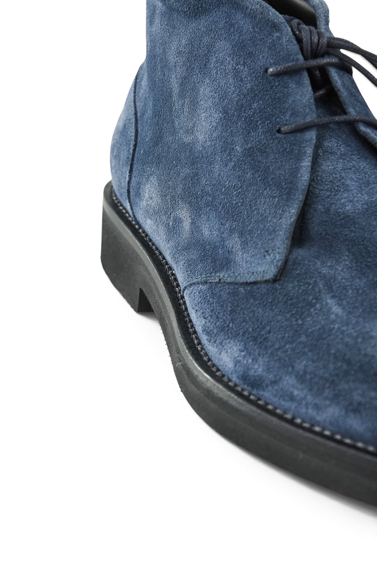 Navy suede chukka boot close-up of laces, vamp seam, and side panel