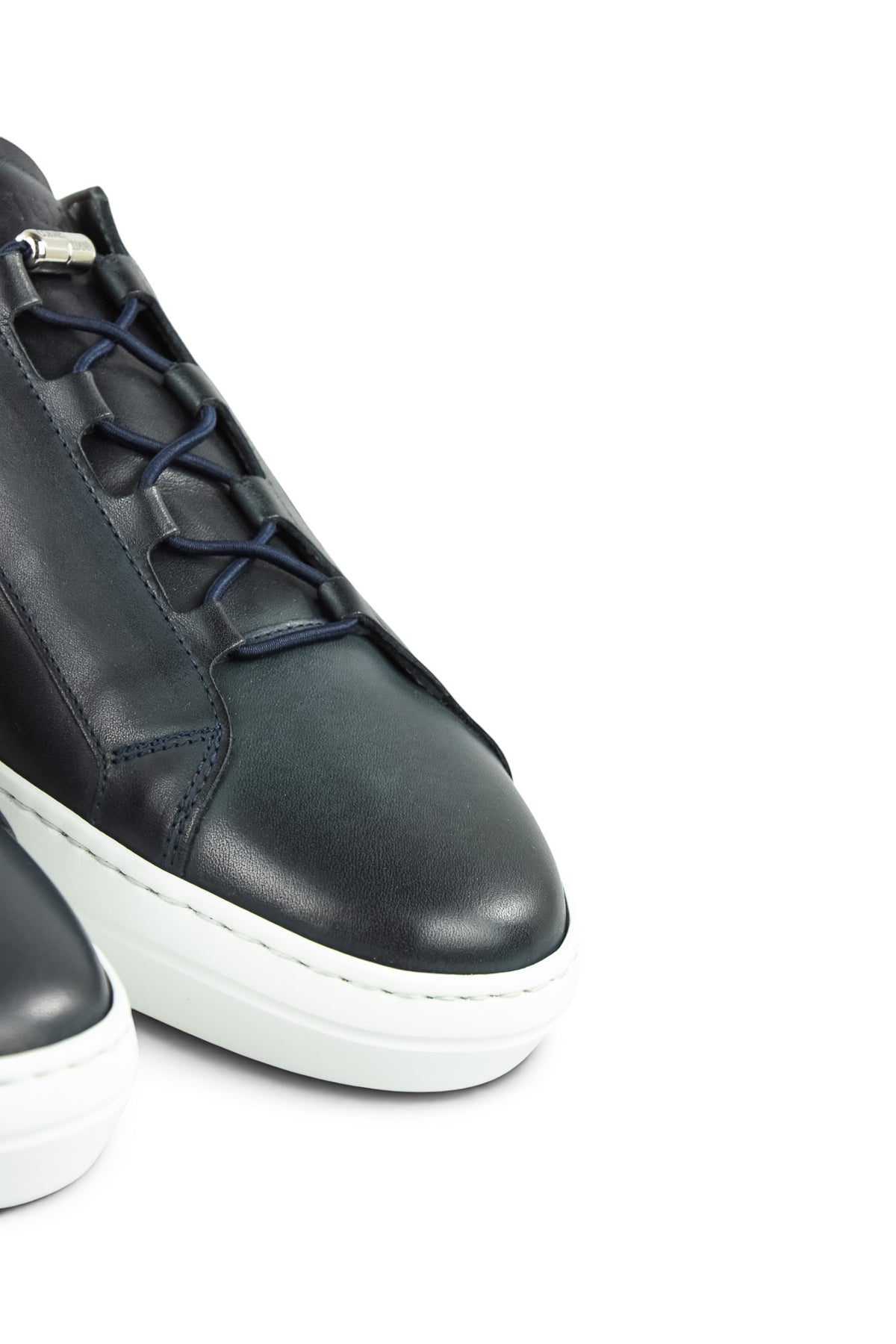 Close-up of navy leather sneaker lace-up detail with white contrast midsole.
