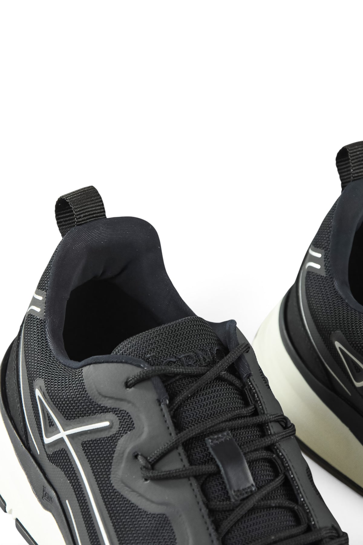 Close-up of black trainer heel and tongue with lace-up top and side logo