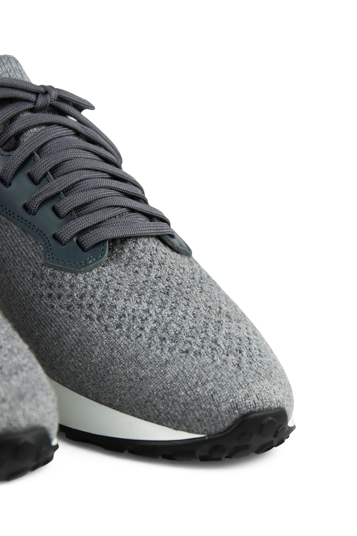 Close-up of grey knitted toe with lace-up vamp and black traction sole