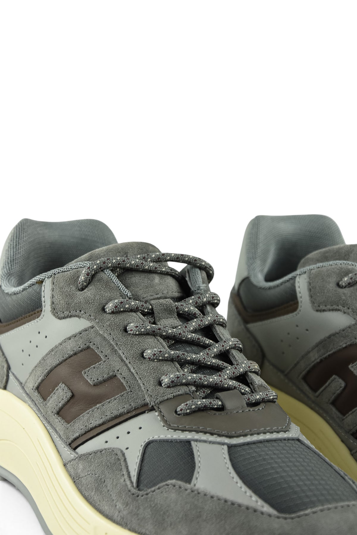 Close-up of grey lace-up trainer showing H logo, laces, and padded tongue