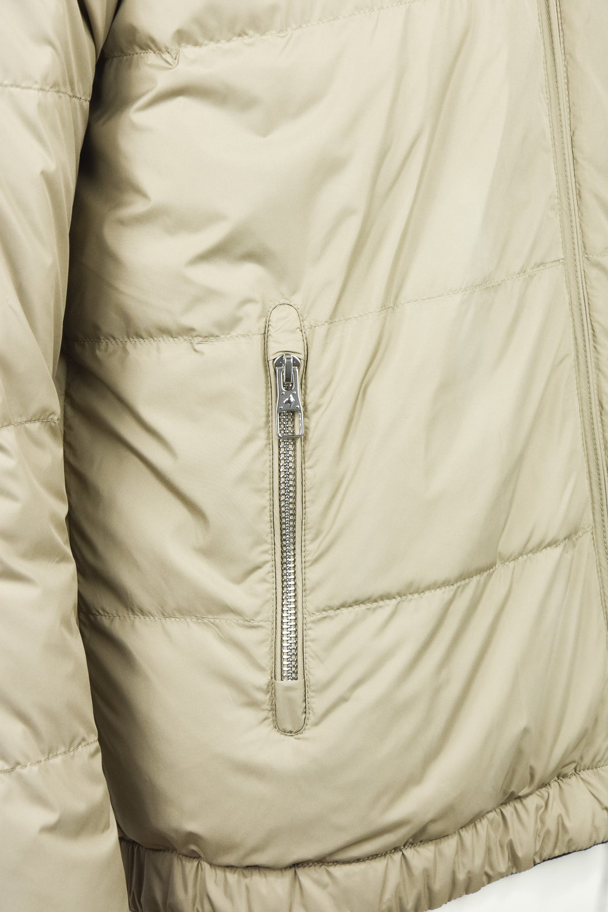 Beige quilted jacket close-up of full-zip slider and stitched panels