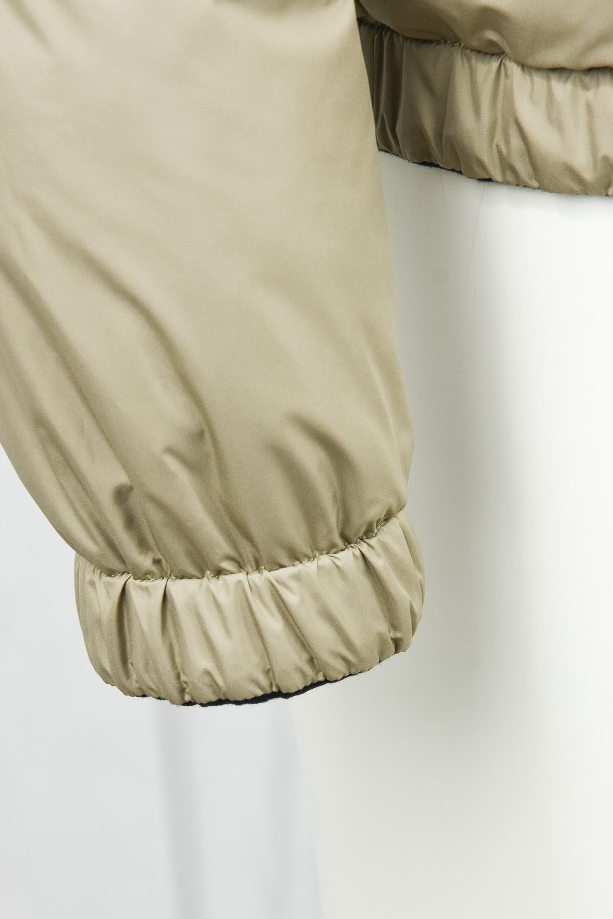Beige quilted jacket sleeve with elastic cuff and stitched paneling