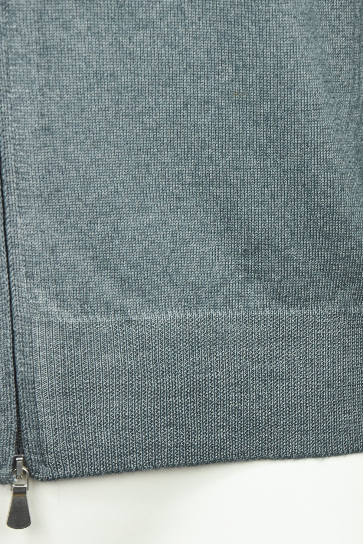 Petrol blue ribbed hem and metal zip on full-zip knit cardigan, close-up.