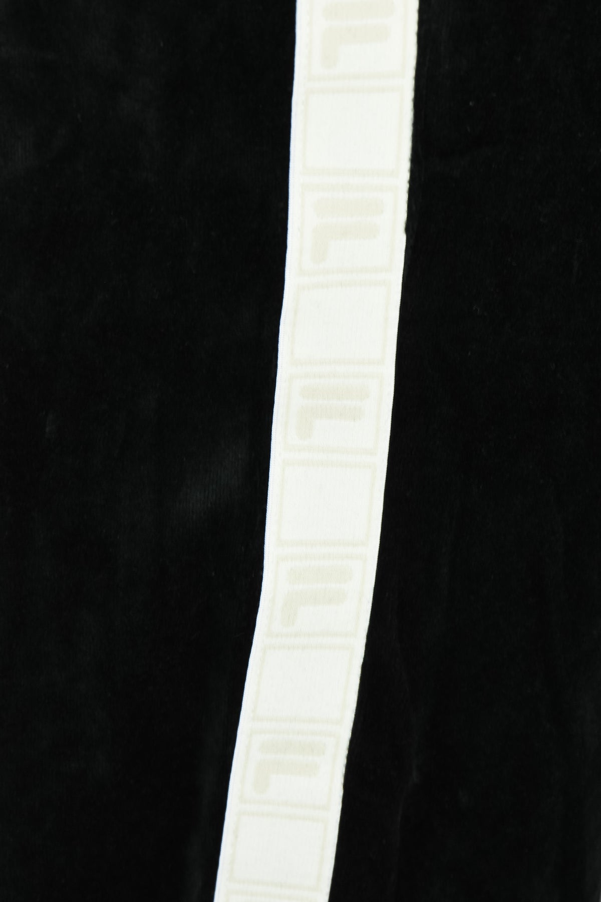 White side tape stripe with repeating Fila lettering on black velour pants