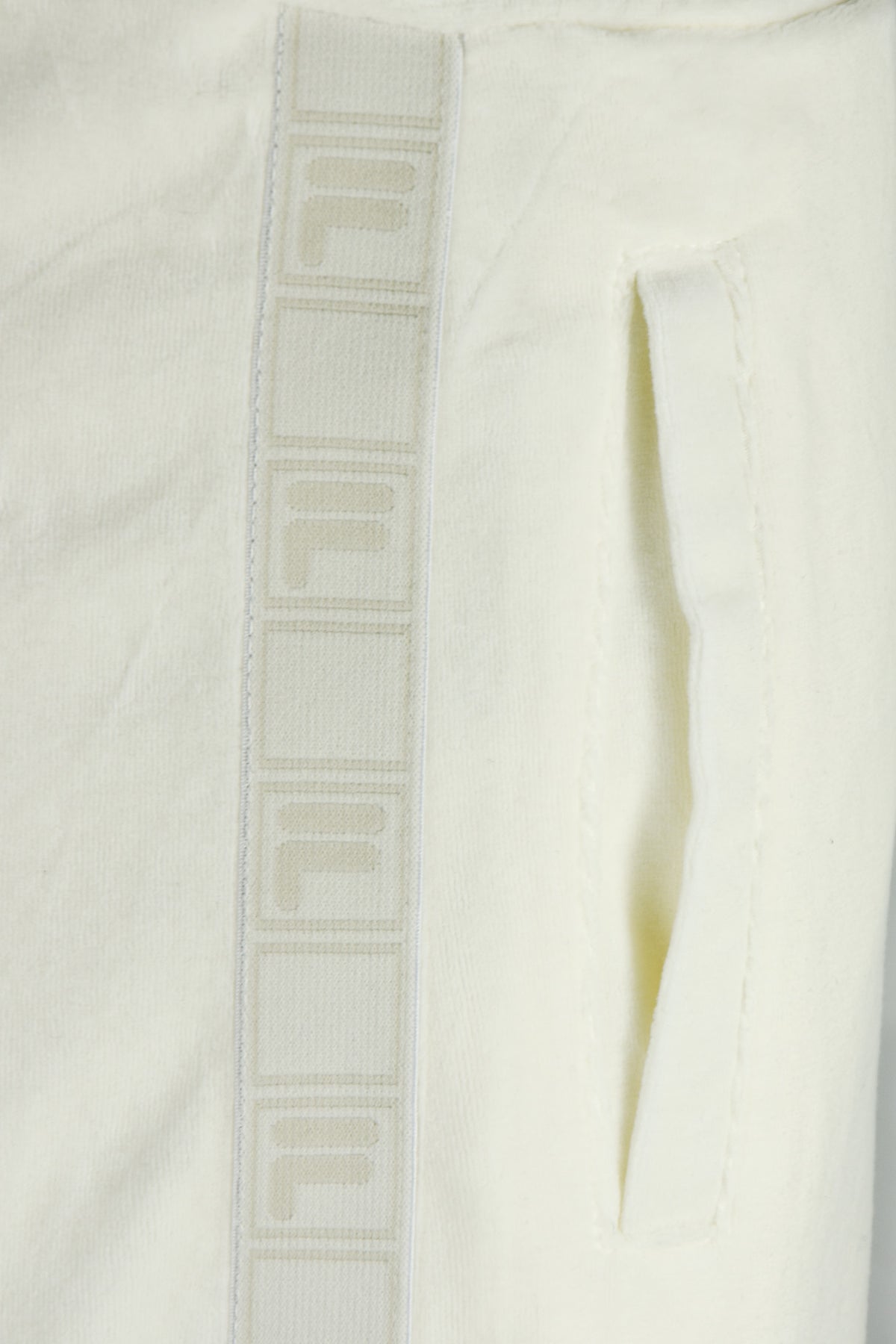 White velour track pants with vertical FILA tape stripe and side opening