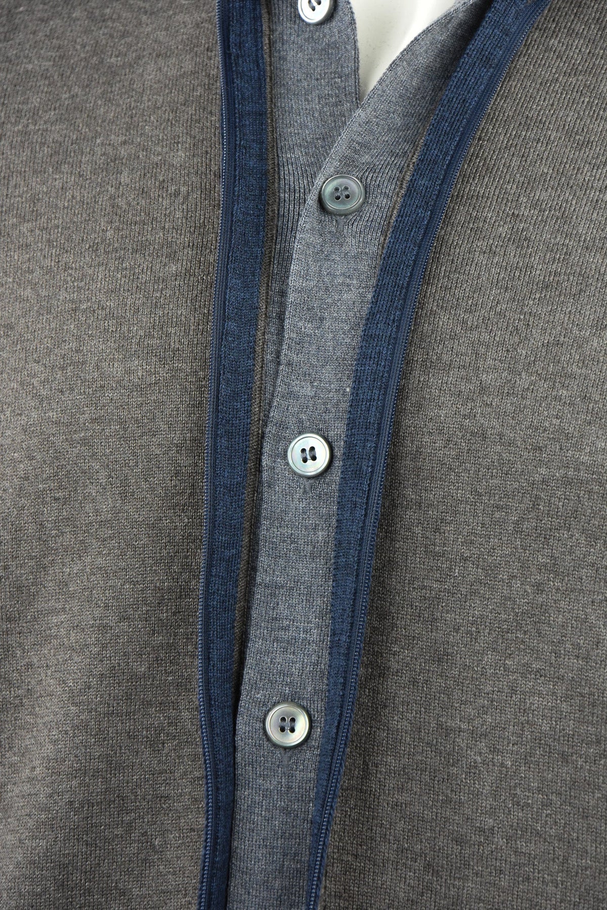 Knitted cardigan close-up showing blue zipper trim and buttoned front placket