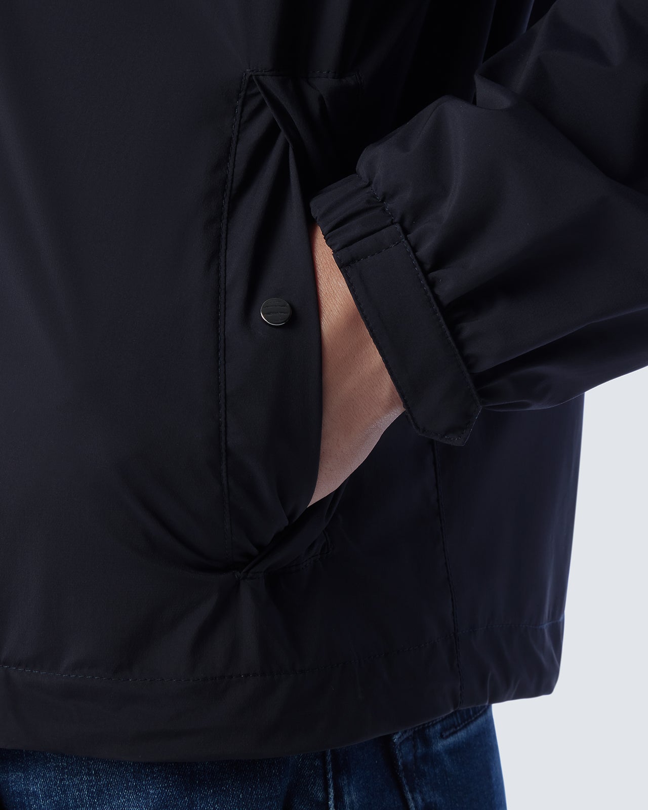 Navy jacket side with buttoned pocket flap and gathered storm panel