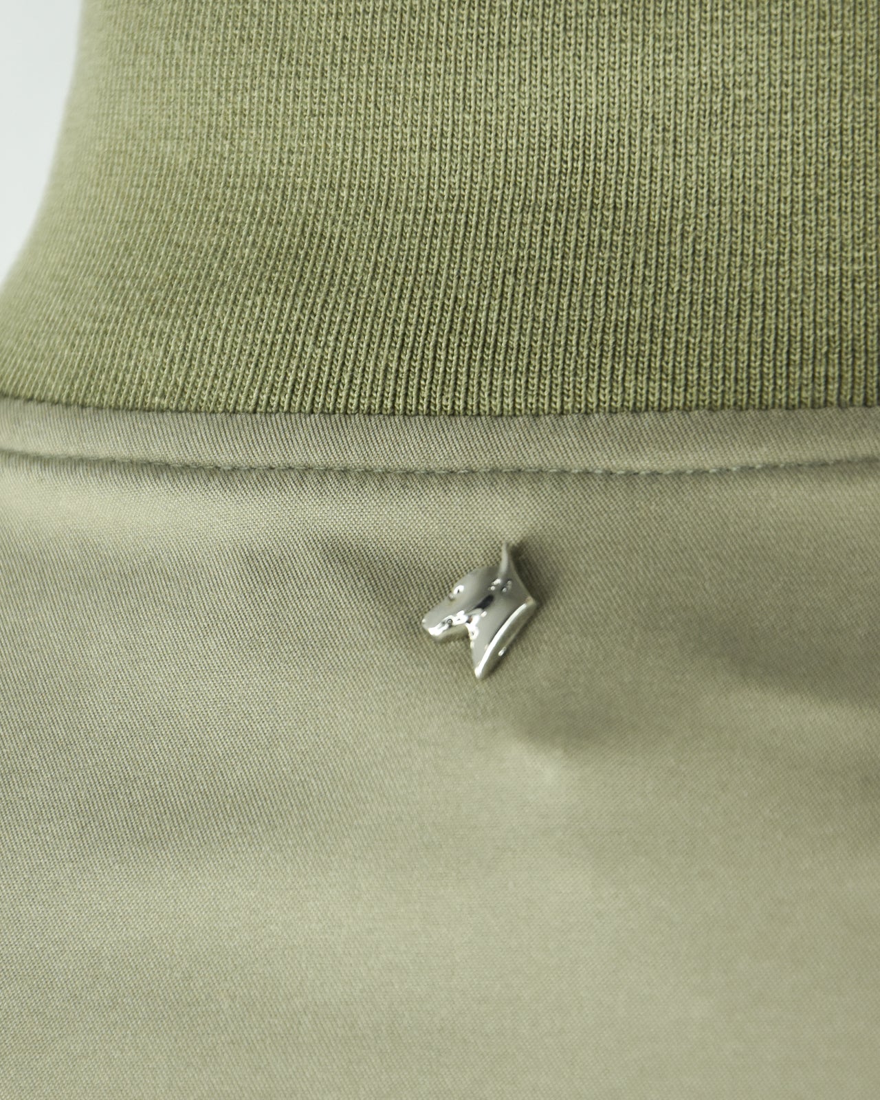 Rib-knit collar on a smoke green blouson jacket with small logo pin