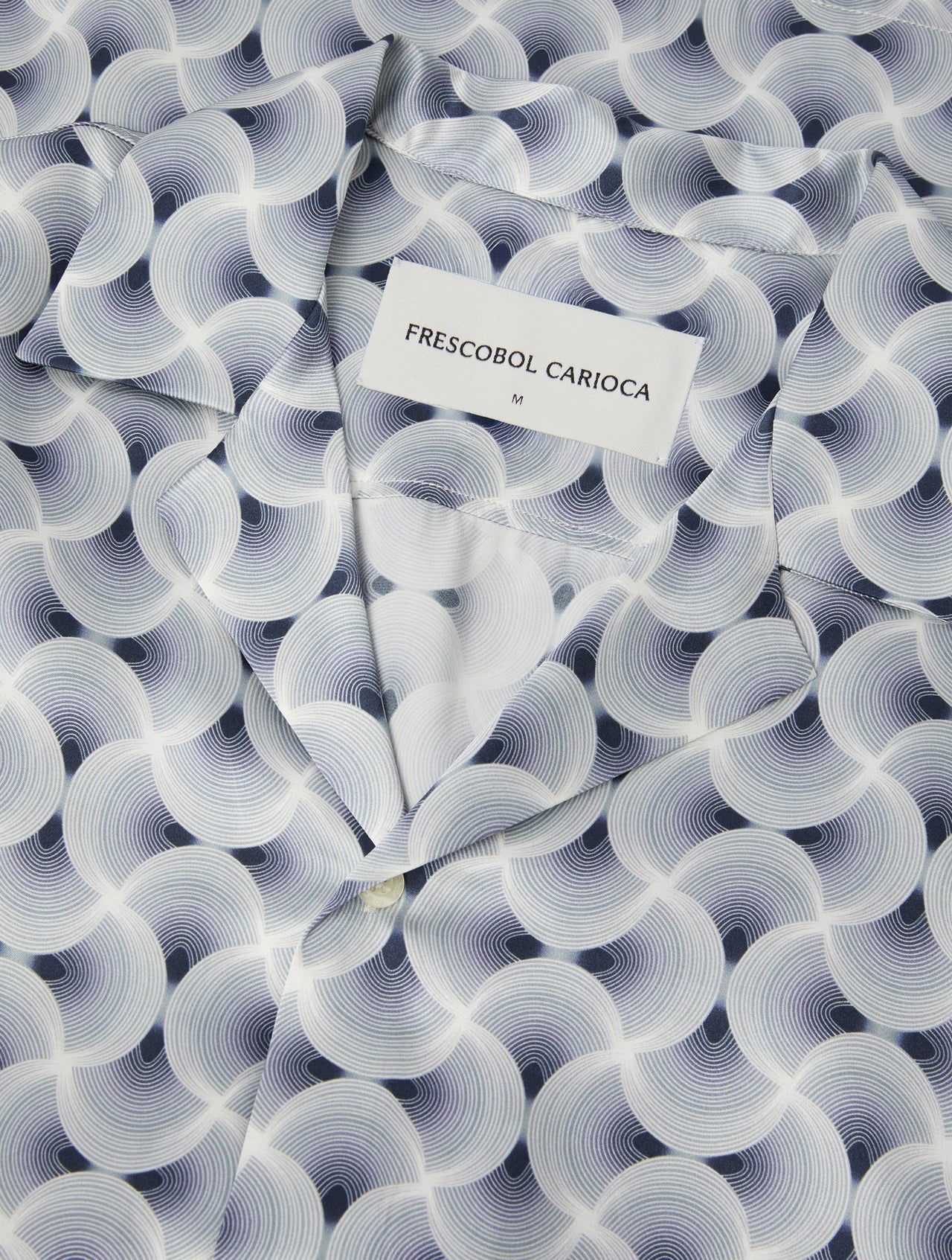 Close-up of short sleeve shirt fabric with swirling spiral print in navy and light blue