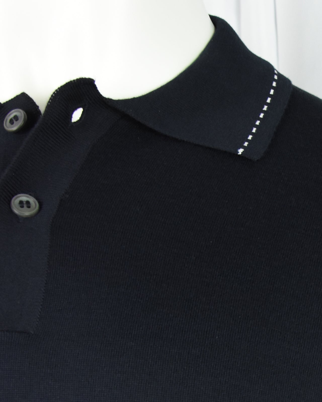 Navy polo shirt close-up of collar, button placket, and contrast topstitch trim