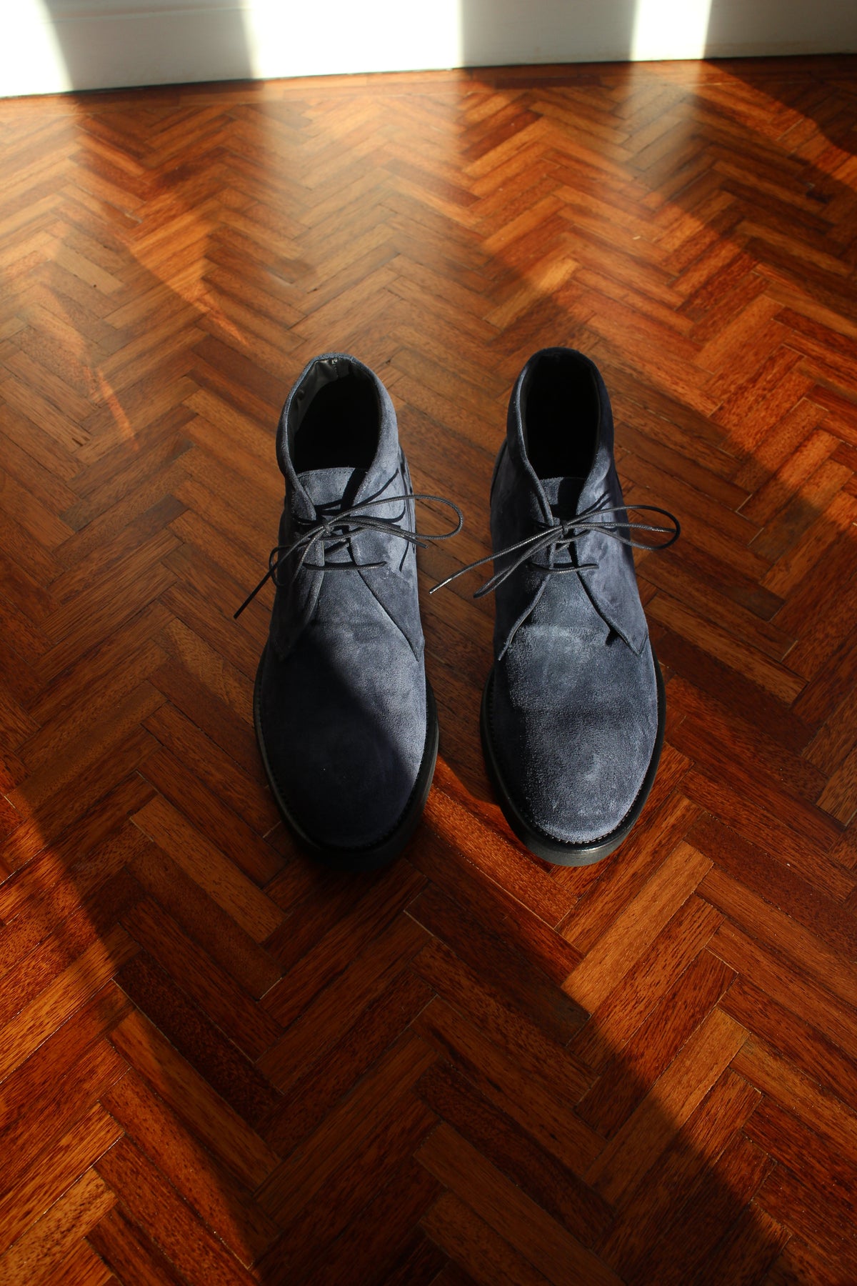 Navy suede chukka boots shown from above with lace-up closure