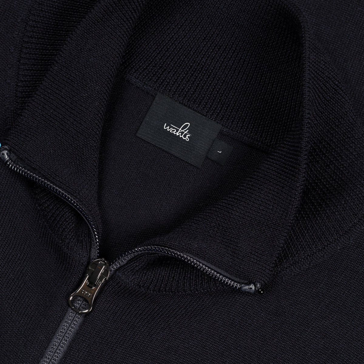 Close-up of dark merino cardigan zipper and WAHTS label at inner neck
