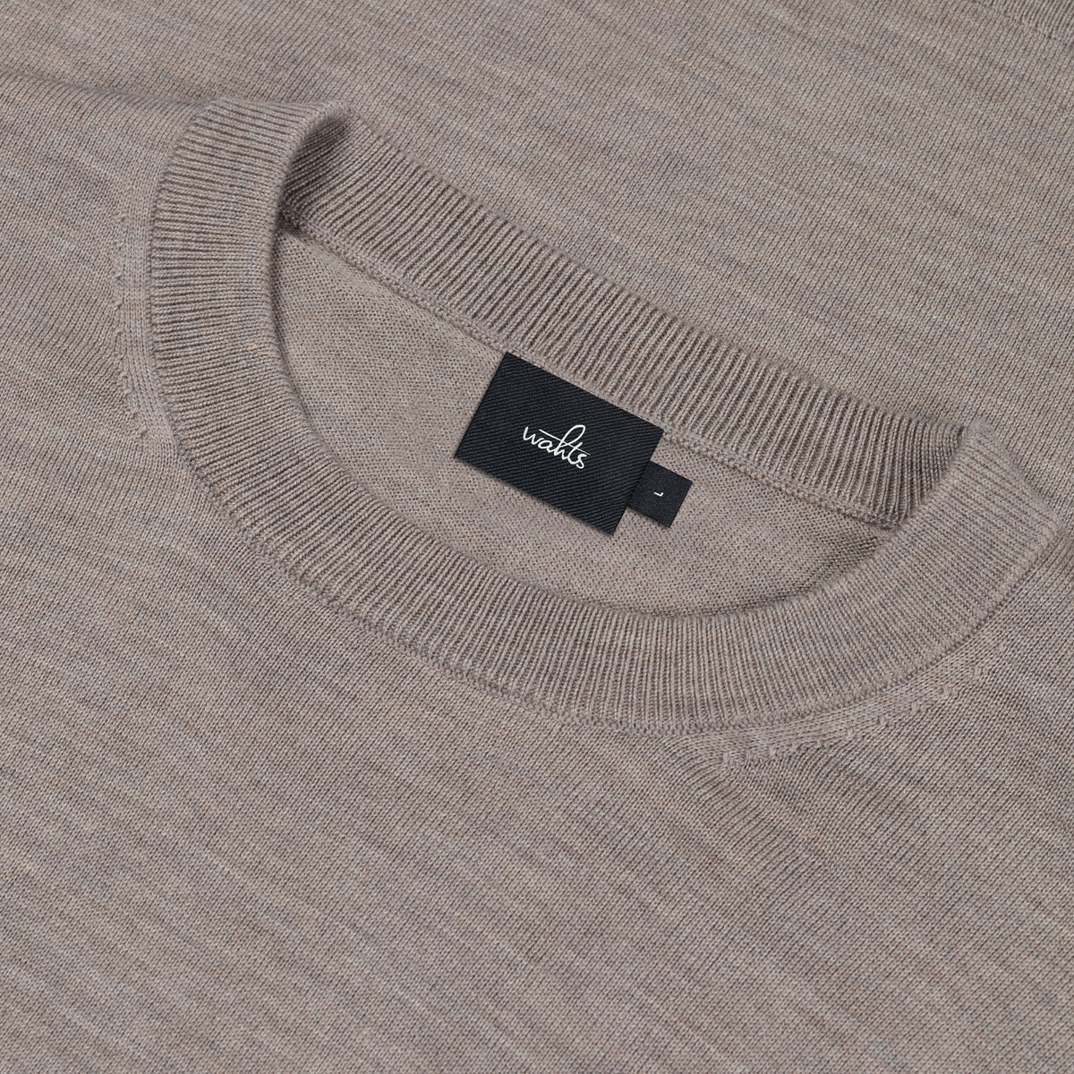 Close-up of light taupe merino crew neckline and WAHTS label tag