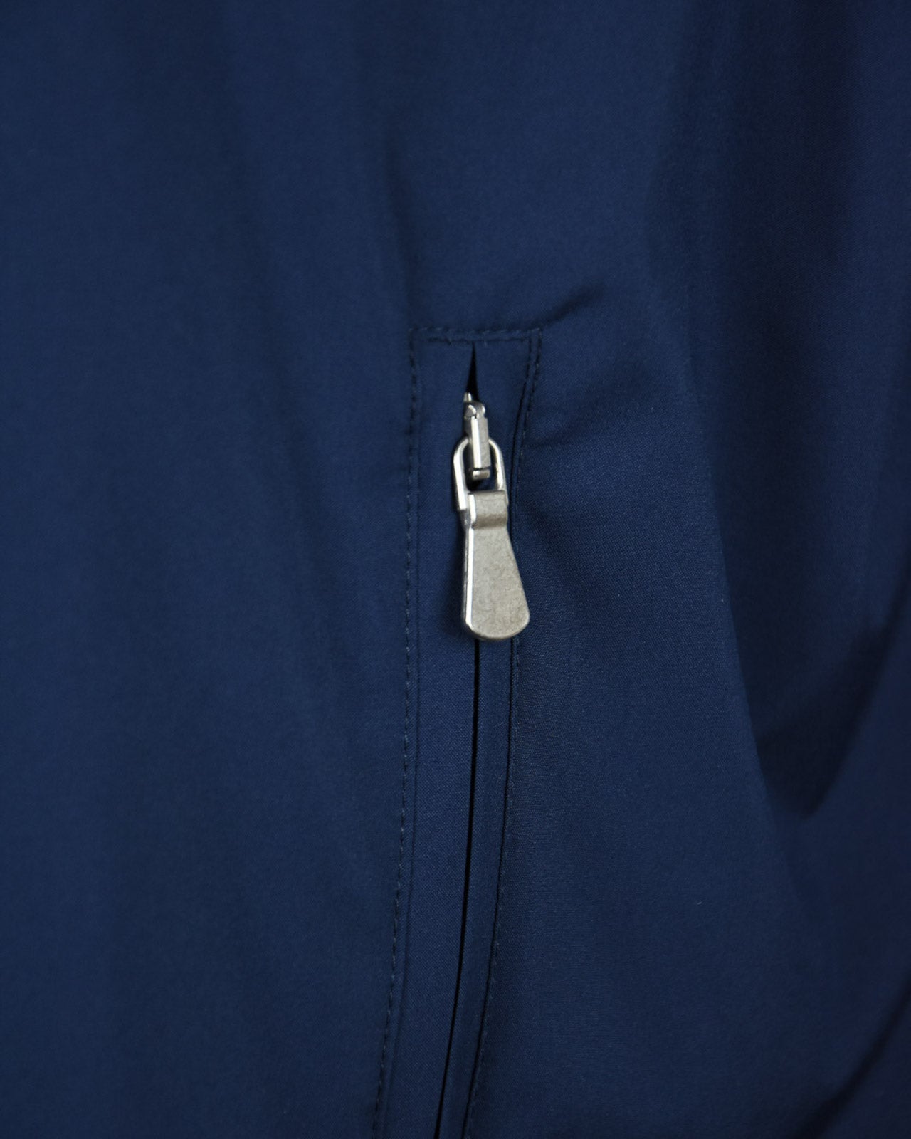 Navy jacket zipper detail with metal pull and stitched placket