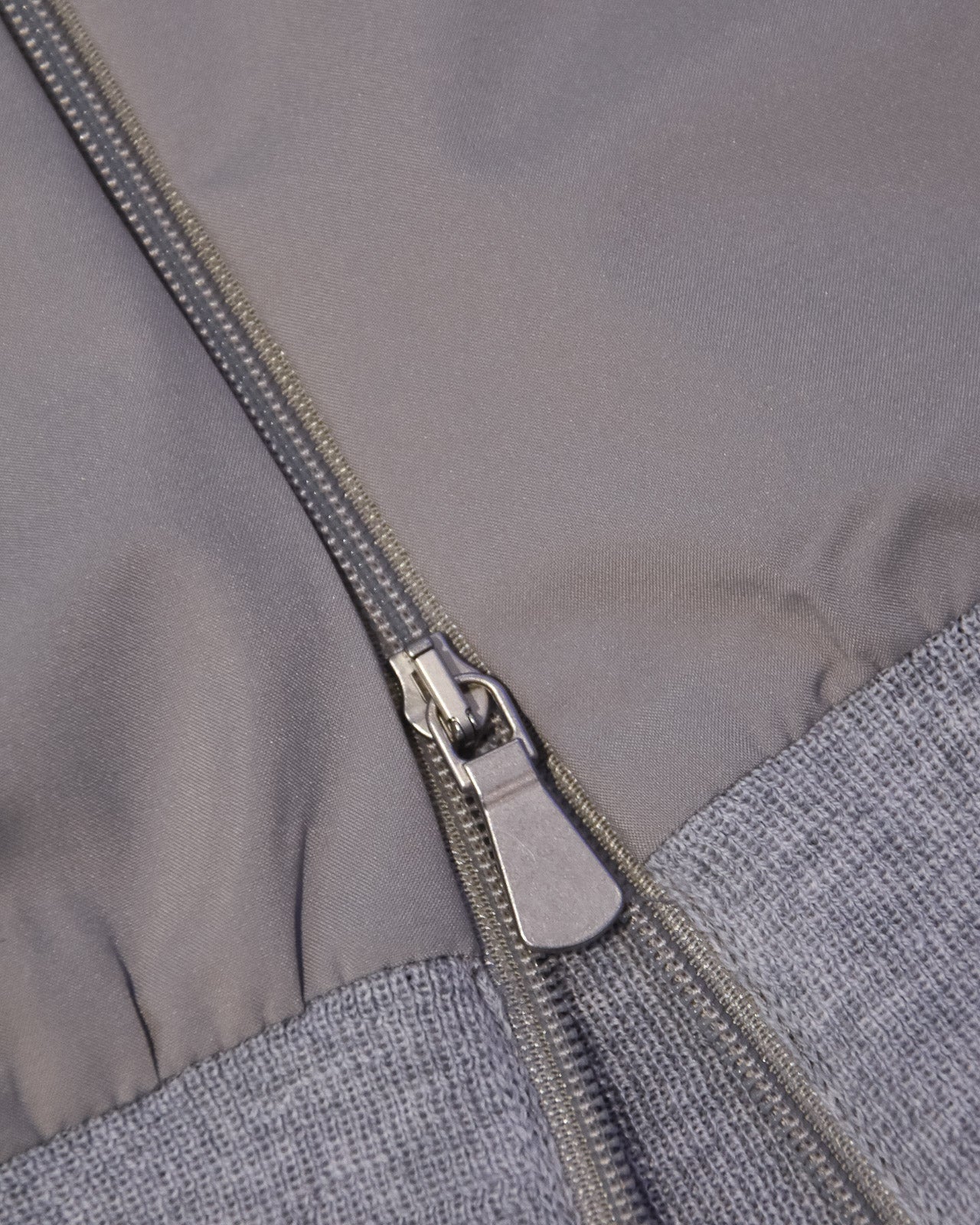 Front zipper detail with silver pull on grey hooded jacket