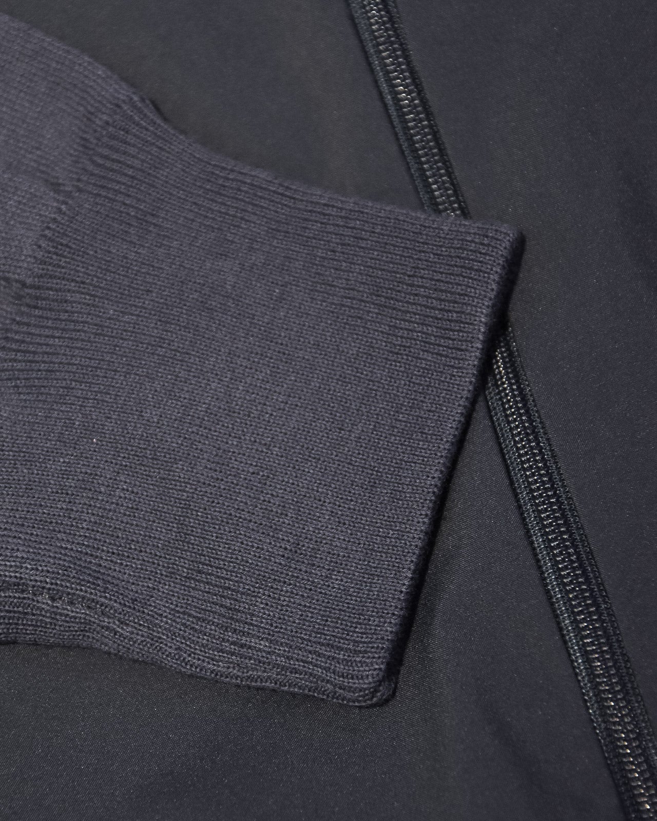Ribbed knit cuff and full zipper on dark hybrid jacket