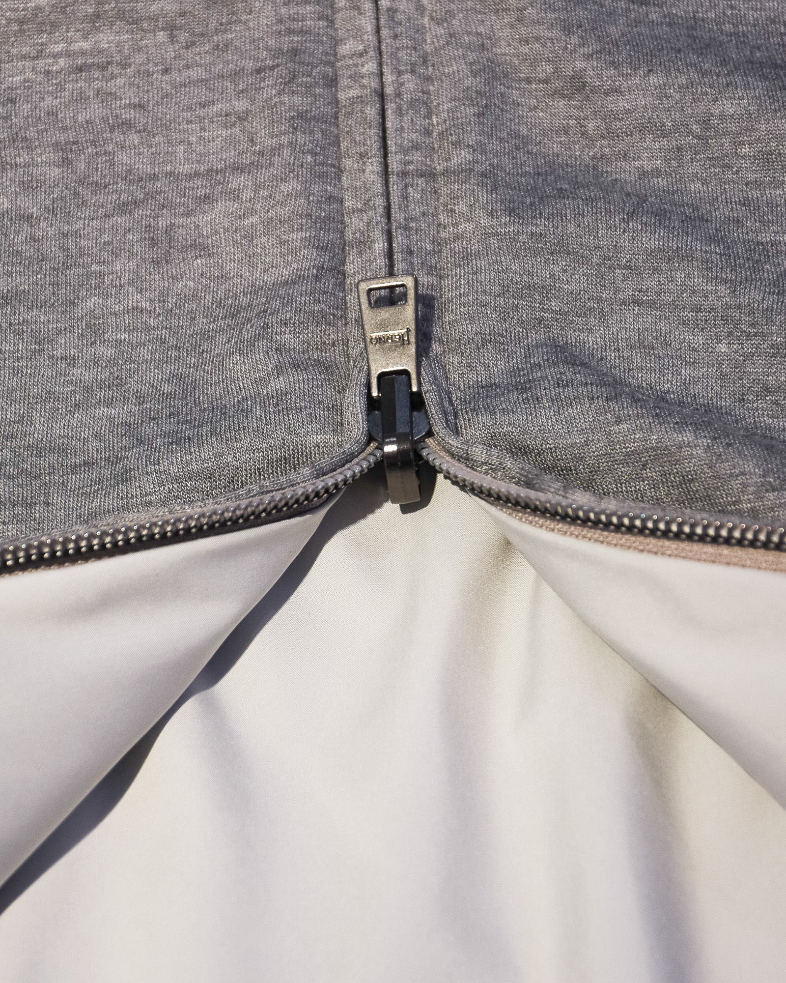 Reversible bomber jacket zipper with black pull and white interior lining at opening