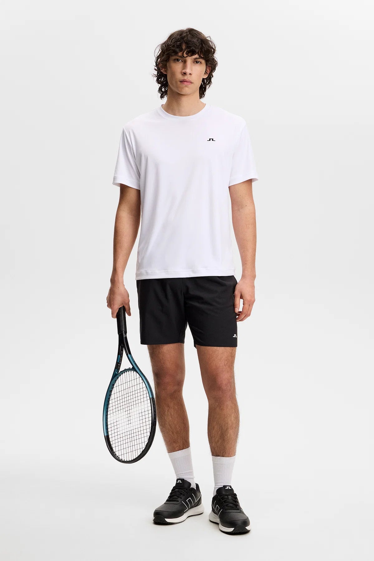 White crew-neck T-shirt worn with black shorts; small chest logo
