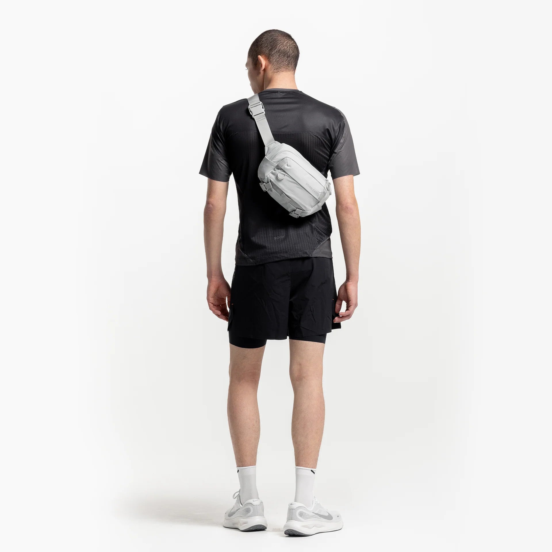 Ash gray sling bag worn from behind with adjustable single shoulder strap