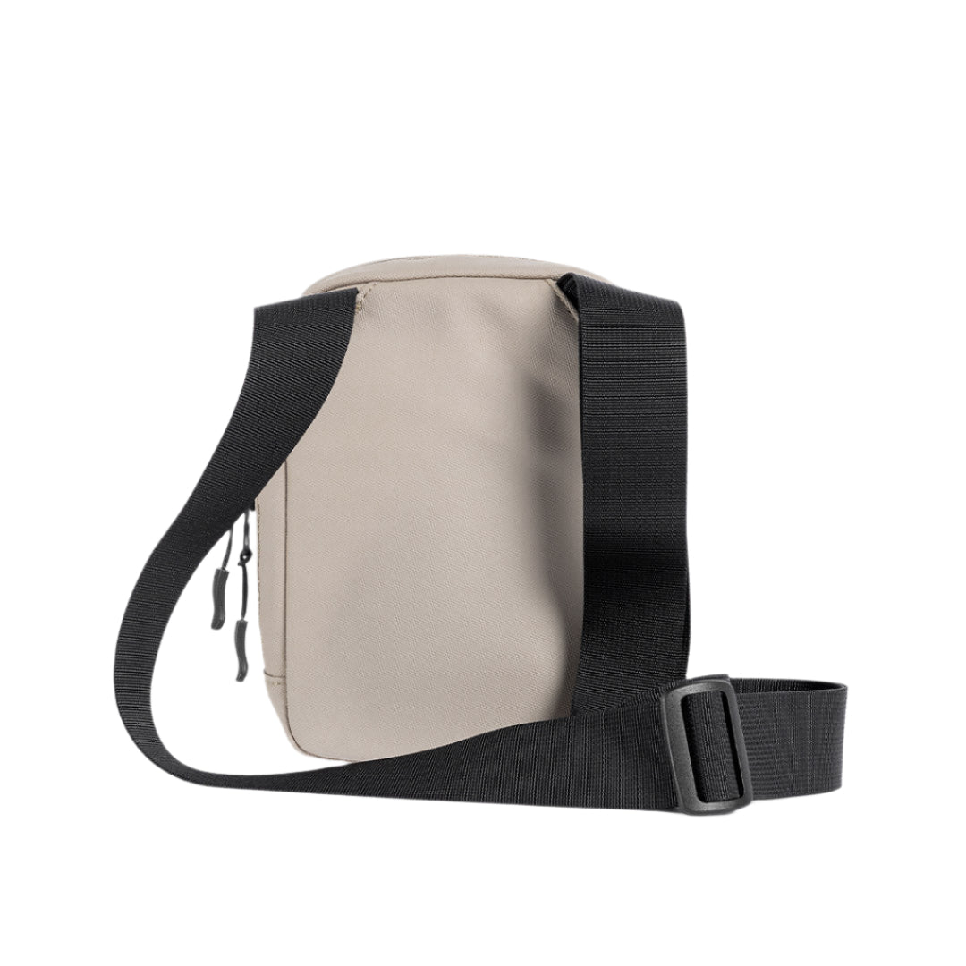 Sand waterproof crossbody bag side view with black strap and zip pull detail