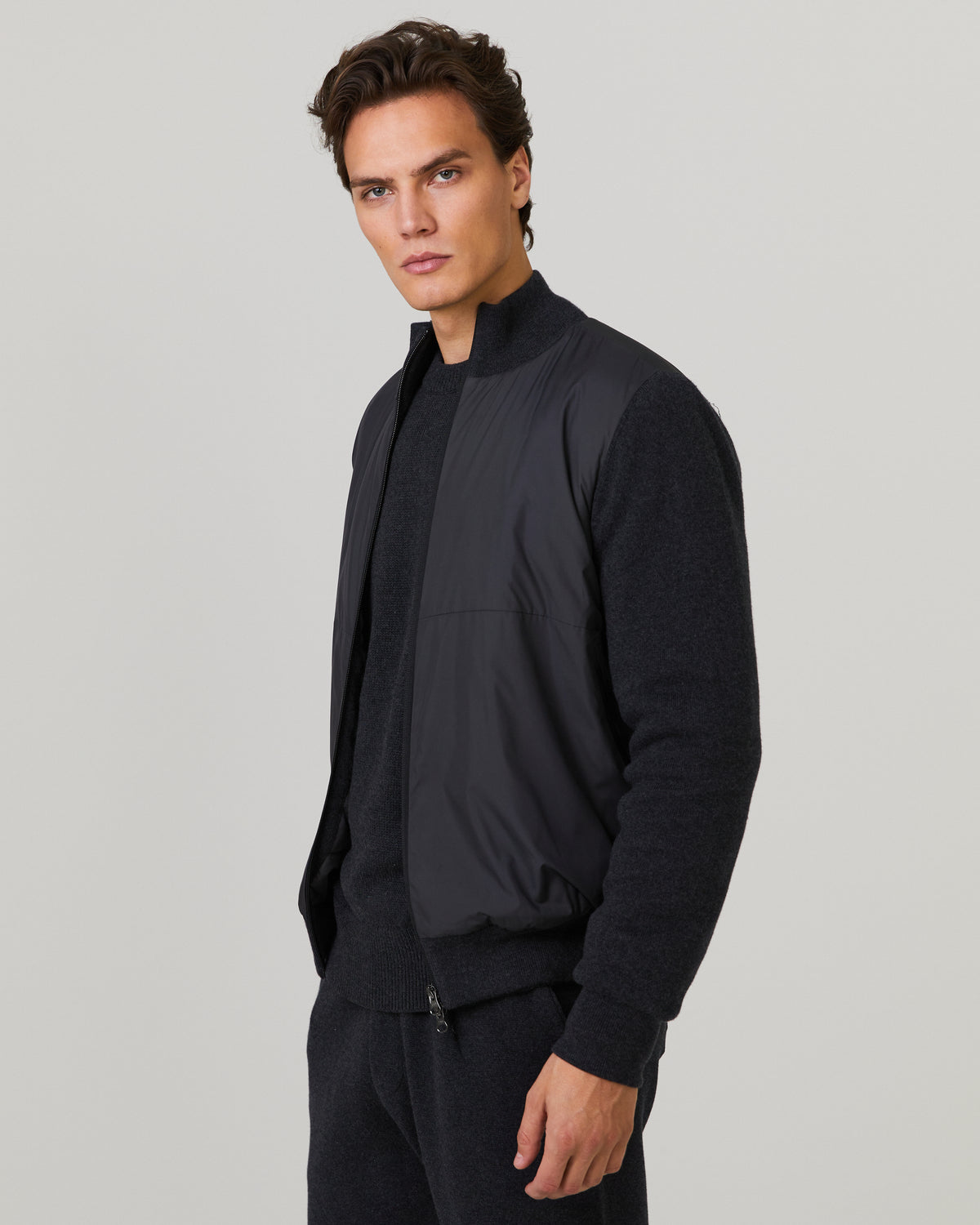 Men's hybrid jacket side view with navy knit sleeves, stand collar, and full zip front.