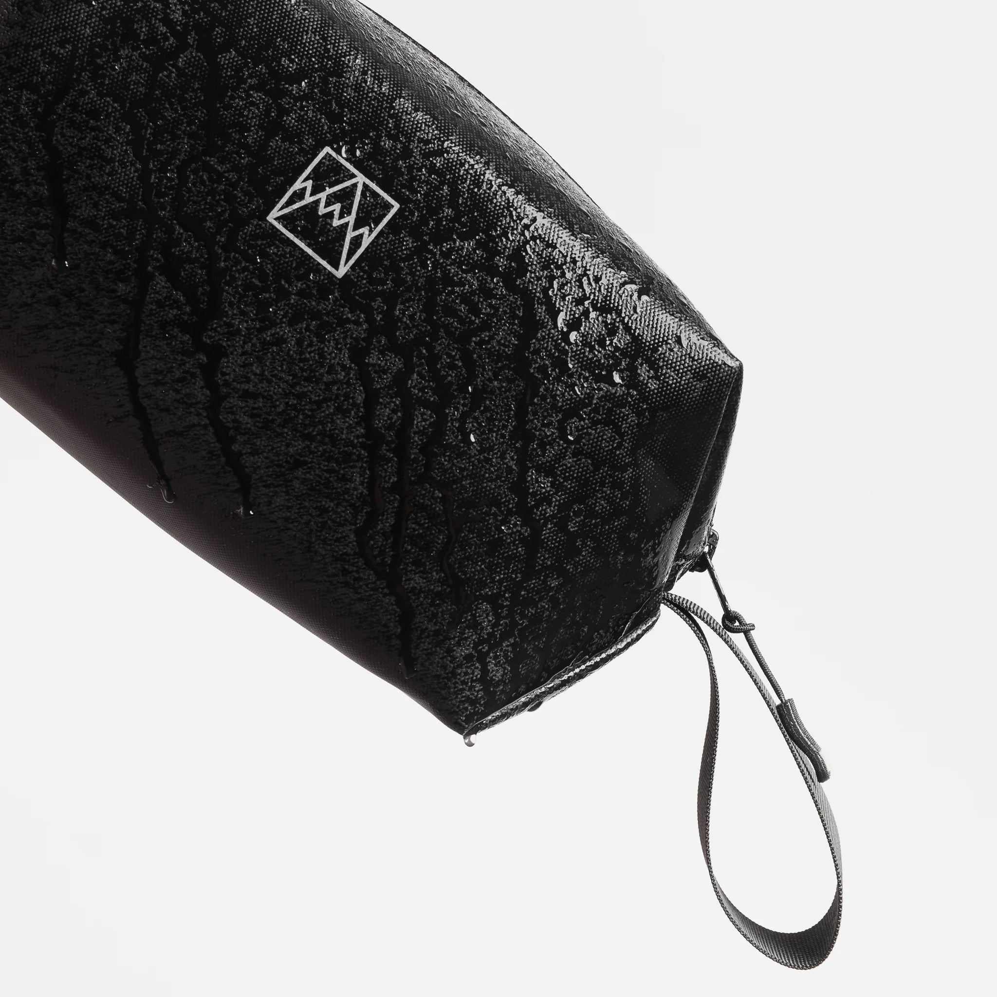 Waterproof wash bag corner detail with zipper and loop wrist strap in dark color.