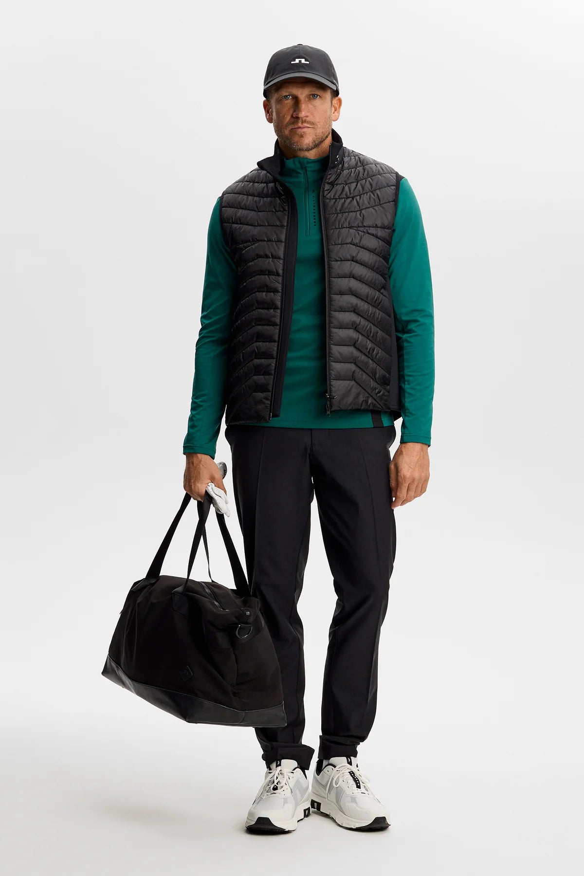 Men's quarter-zip mid layer with black quilted sleeveless vest over teal top