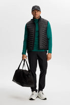 Men's quarter-zip mid layer with black quilted sleeveless vest over teal top
