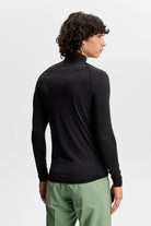 Black long-sleeve compression mock-neck top shown from back, with fitted waist.